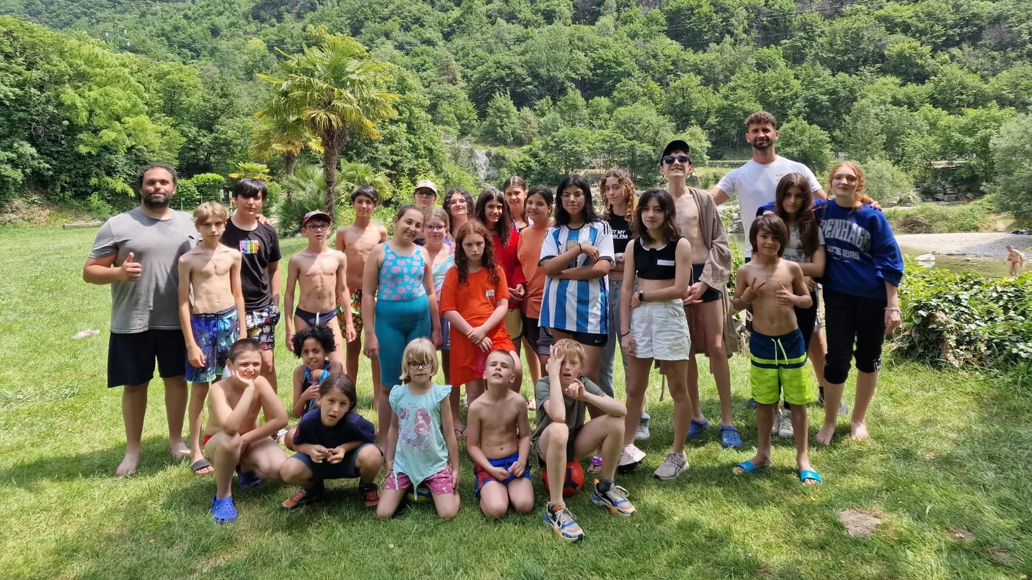 Foto di gruppo dei bambini e degli animatori del camp, immersi nel verde