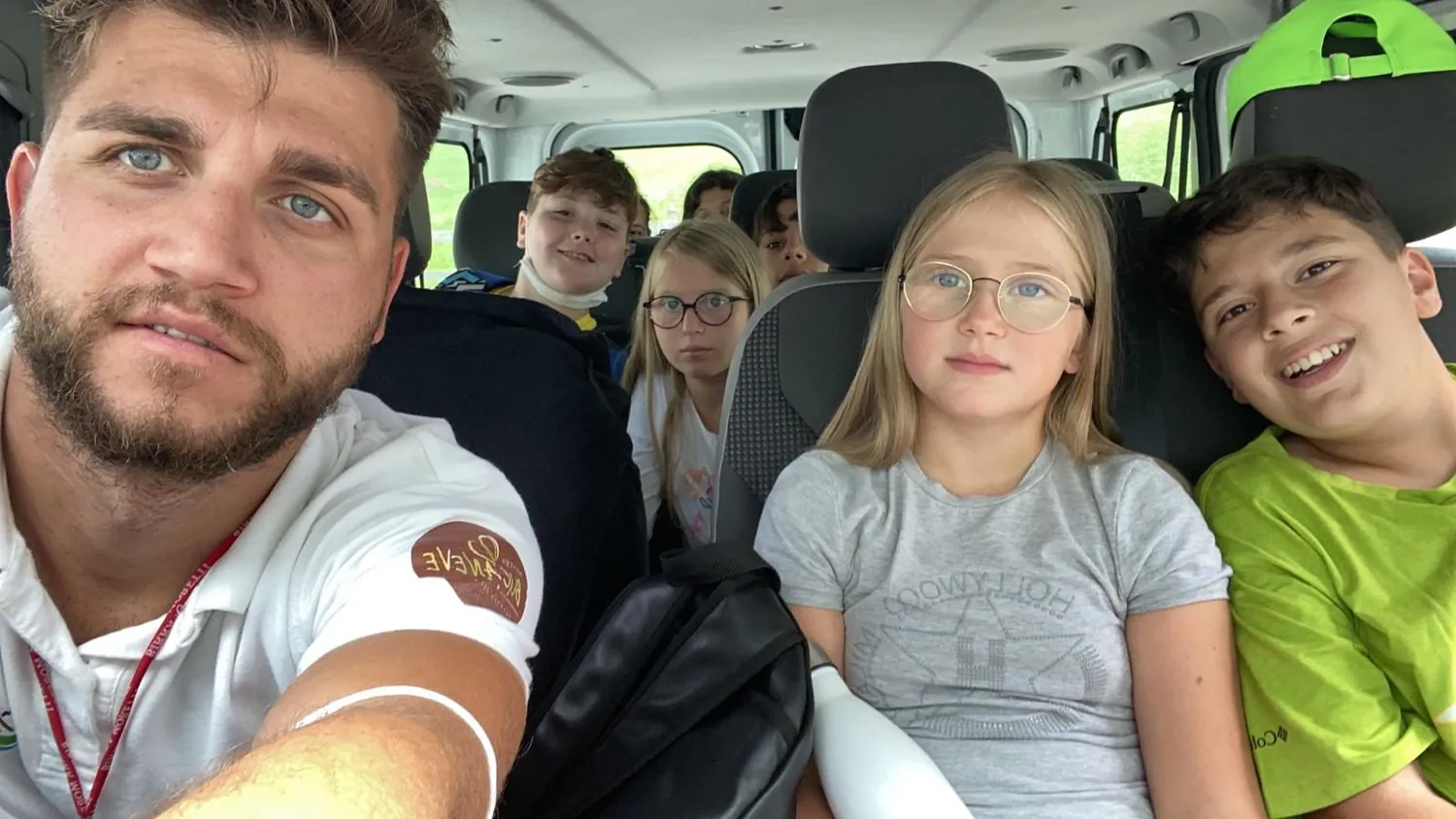 Un animatore del camp si fa un selfie coi bambini sul pulmino in partenza