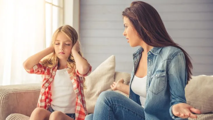 Una mamma e la figlia adolescente discutono sul divano per il telefono