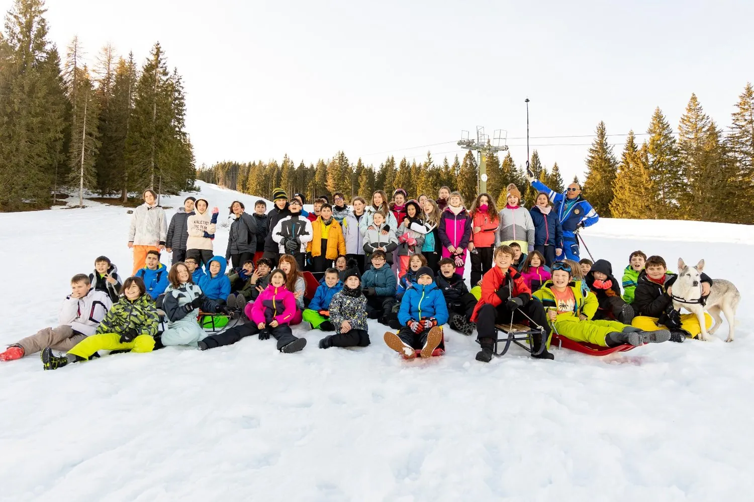 Gruppo di bambini sulla pista innevata con un husky