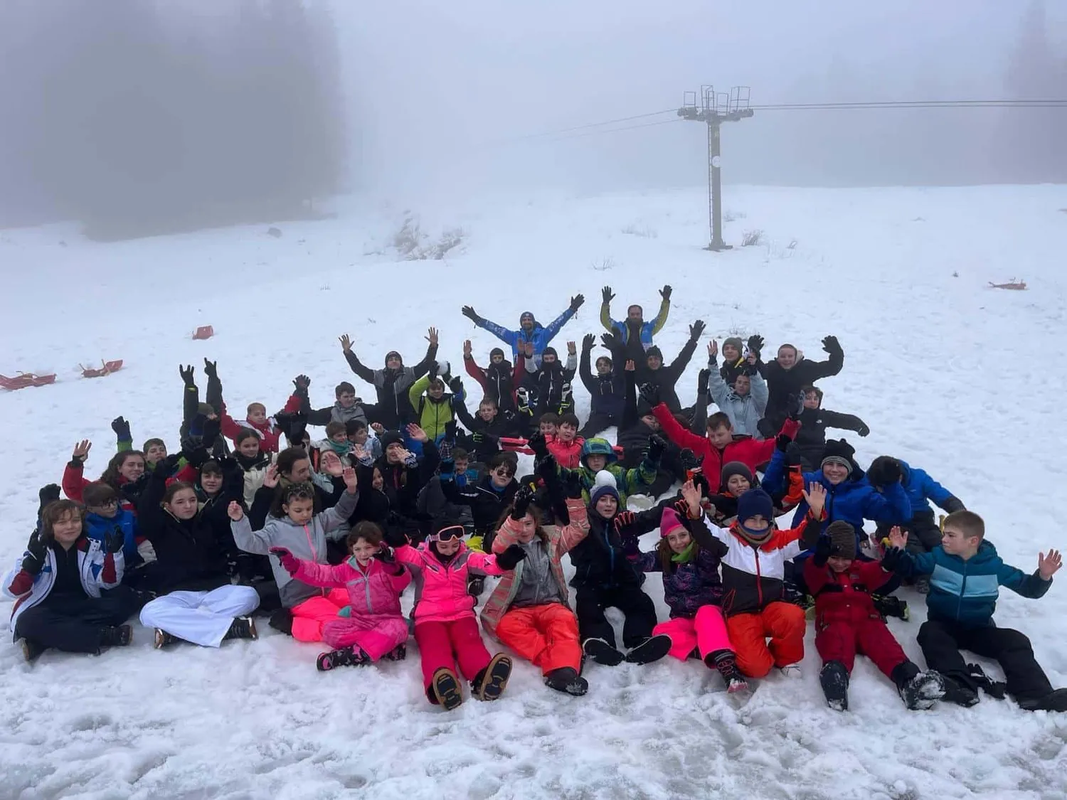Gruppo di bambini del Camp sulla neve con le mani alzate